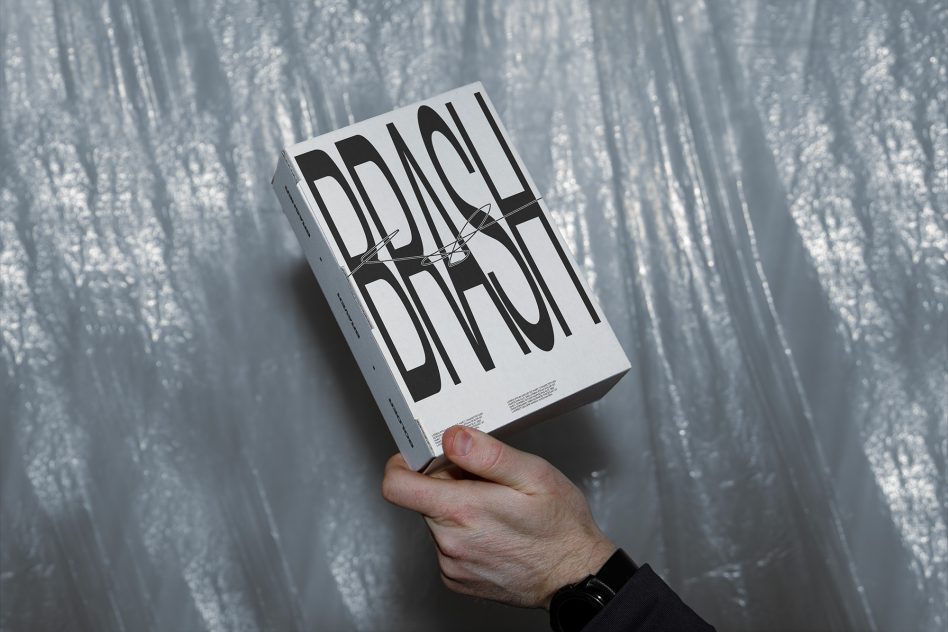 Hand holding white box with bold black striped layered text design